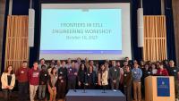 A large group of participants stands together in front of a screen showing “Frontiers in Cell Engineering Workshop – October 10, 2025.”